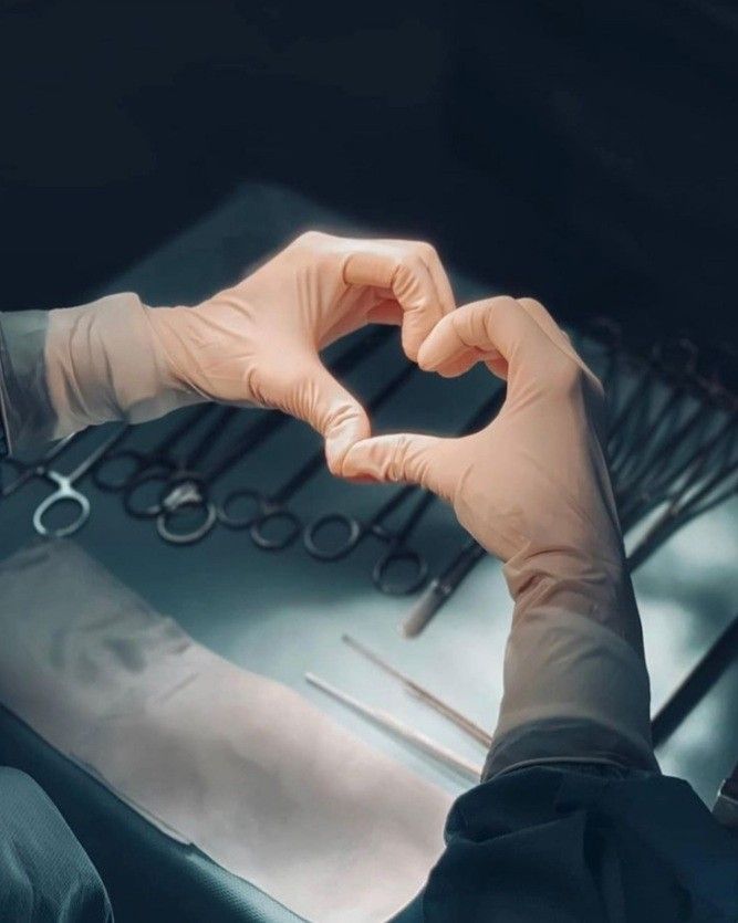 a person wearing gloves making a heart shape with their hands