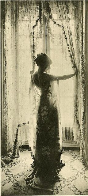 an old photo of a woman standing in front of a window with her arms outstretched