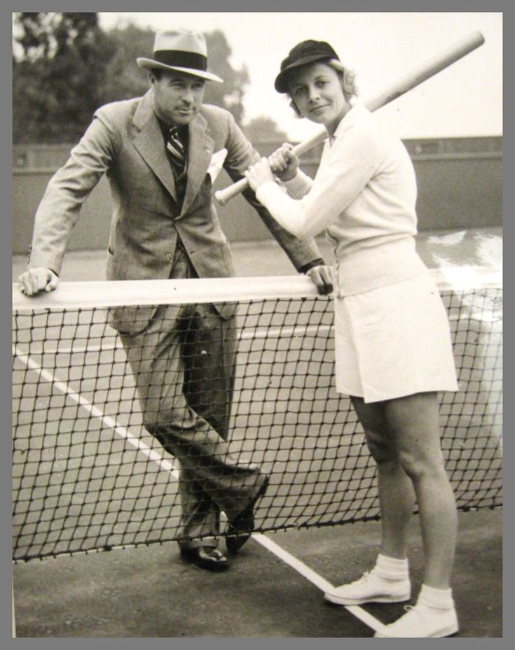 an old black and white photo of a man and woman holding tennis racquets