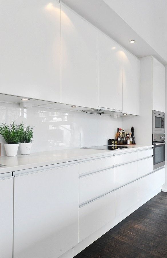 a kitchen with white cupboards and counters in the center, along with potted plants on the counter