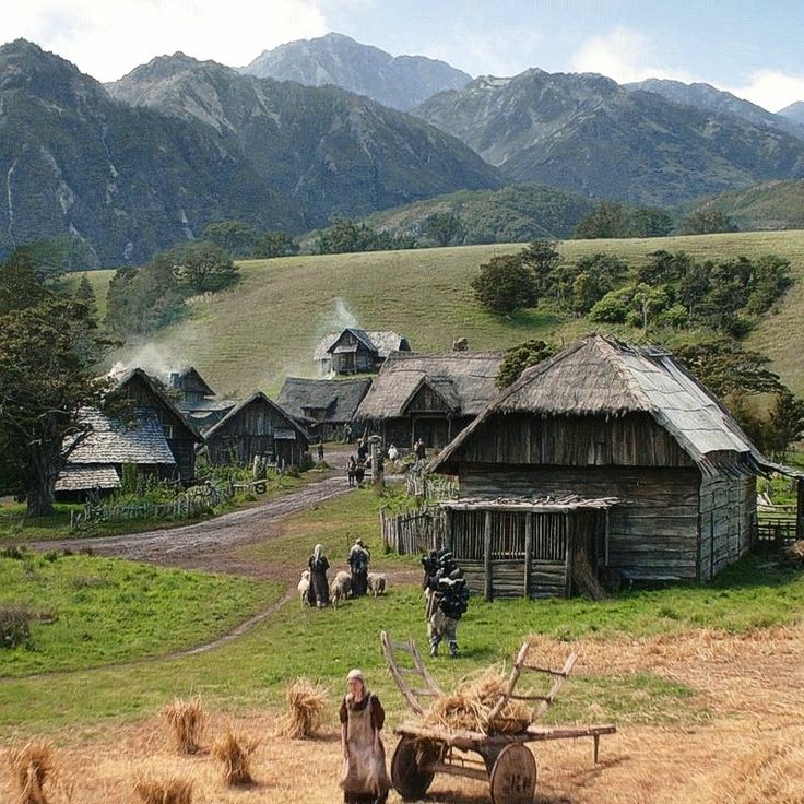 an old village in the mountains with people walking around it and horses pulling hay behind them