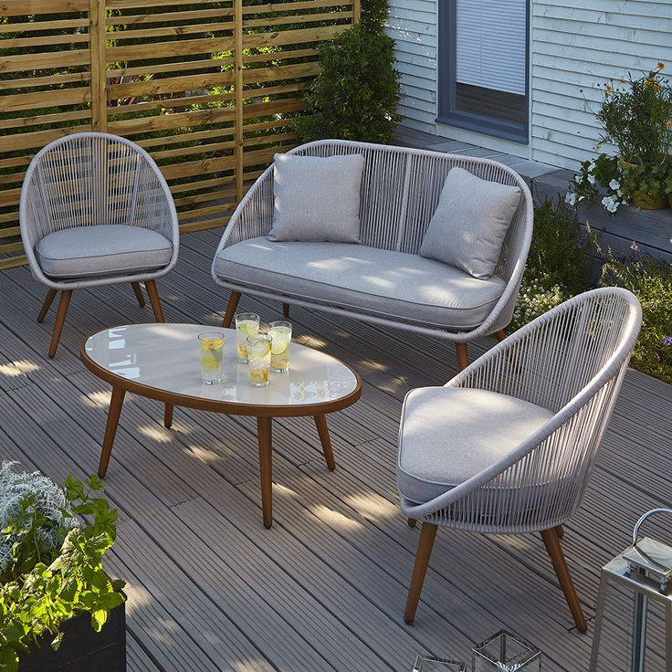 three wicker chairs sitting on top of a wooden deck next to a coffee table