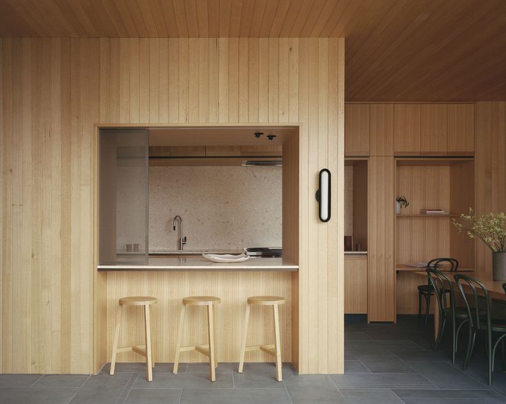 a kitchen with wooden walls and stools next to a counter top that's built into the wall