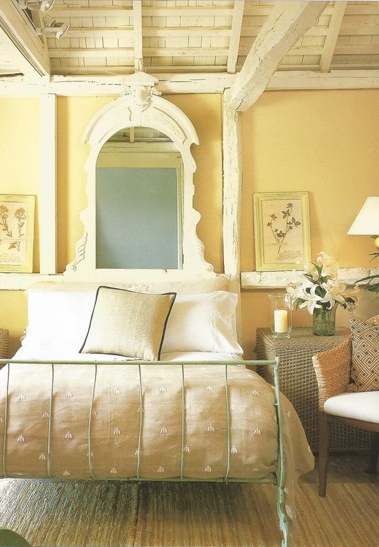 a bedroom with yellow walls and white furniture