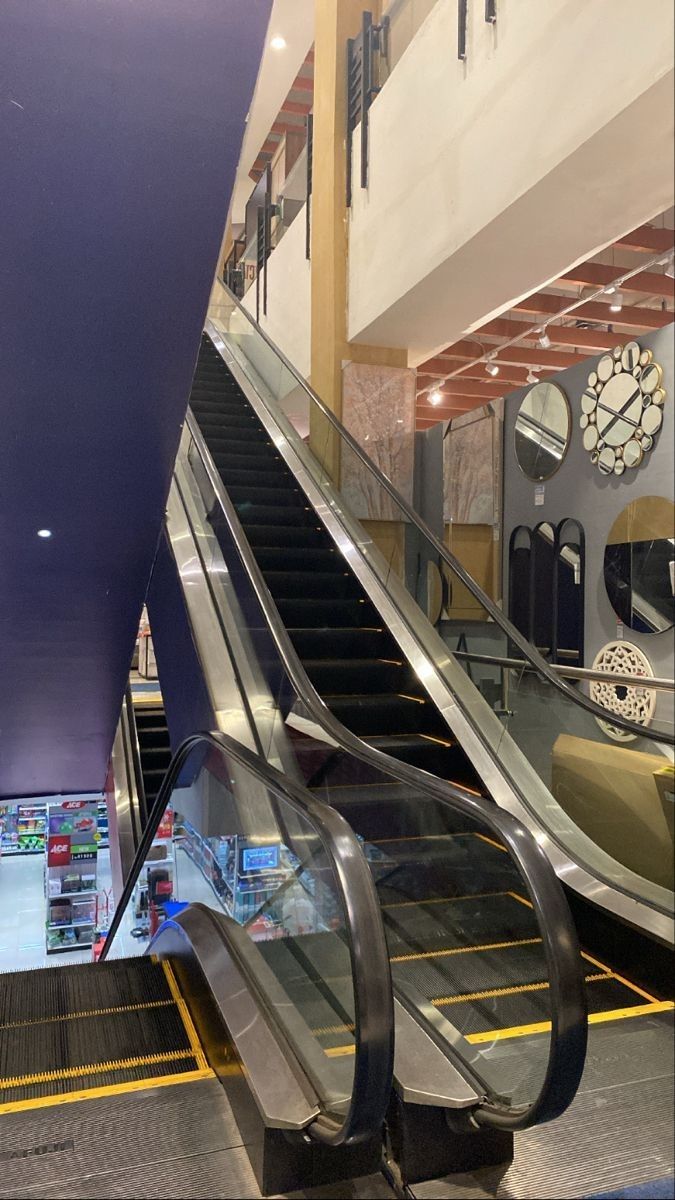 an escalator in a shopping mall with people walking up and down the stairs