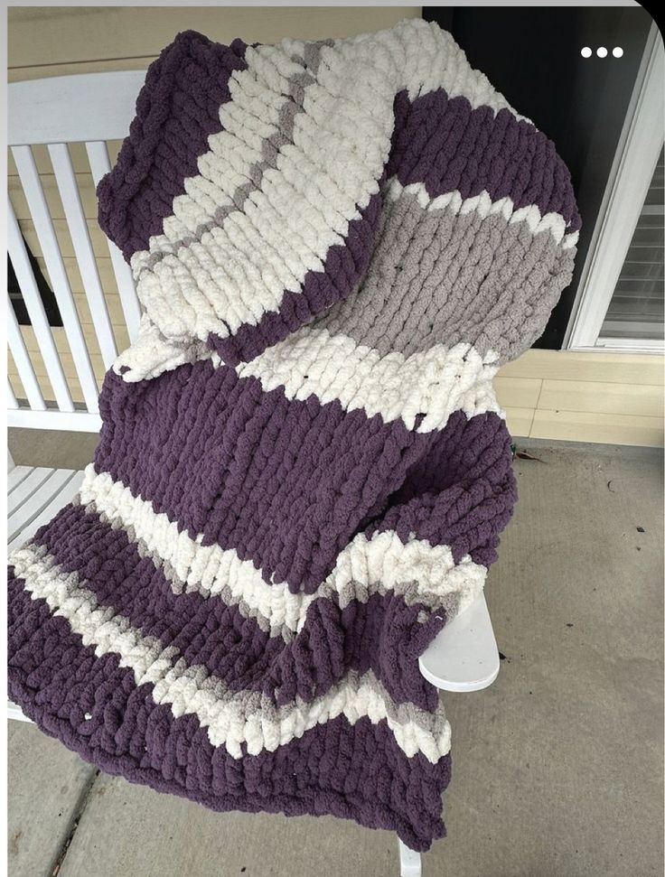 a purple and white blanket sitting on top of a chair