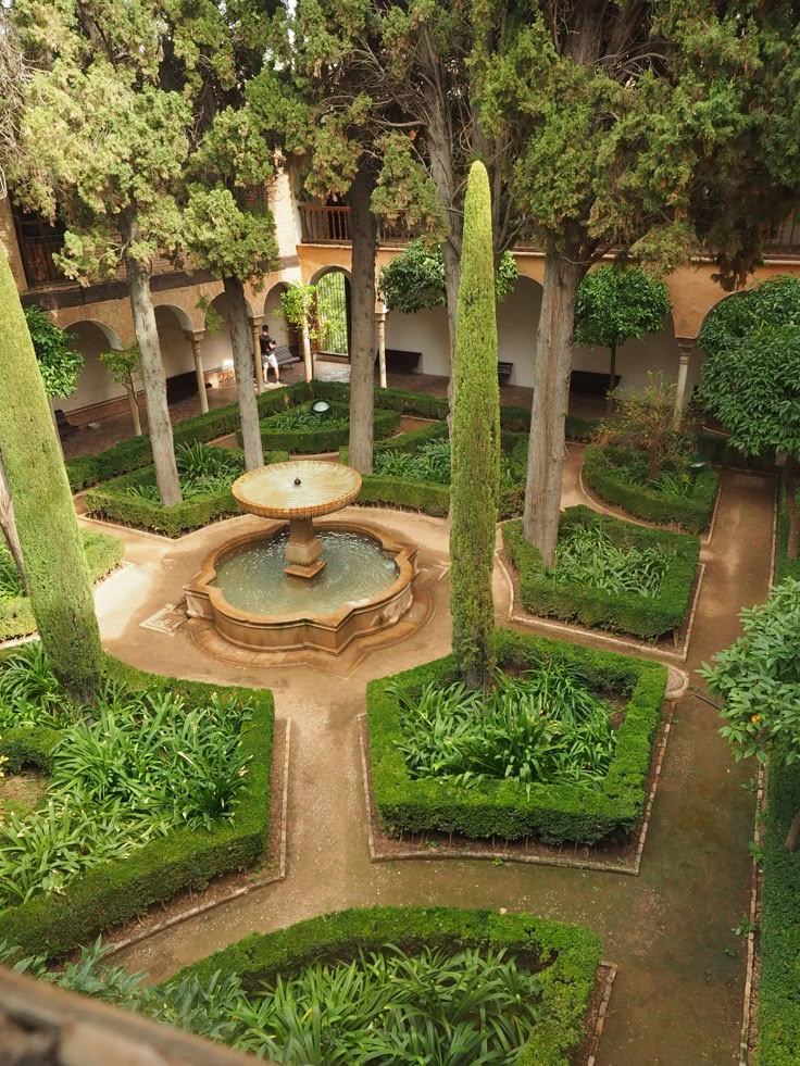 the garden is surrounded by many trees and bushes, with a fountain in the center