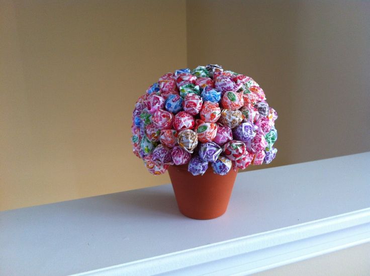 a vase filled with lots of candy covered in colorful candies on top of a white shelf