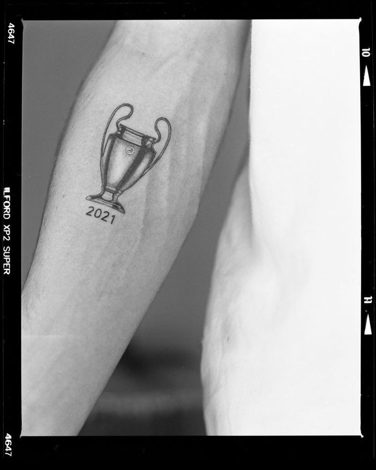 two people with tattoos on their arms holding hands and one has a trophy tattoo on the arm