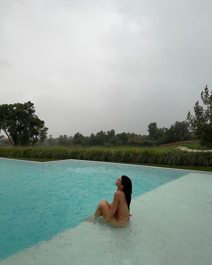 a woman is sitting in the middle of a swimming pool and looking up into the sky