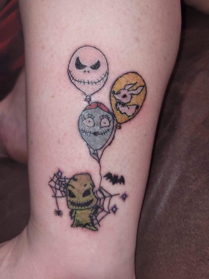 a person with a tattoo on their leg that has three balloons attached to it and two faces