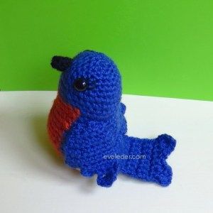 a crocheted blue and red toy sitting on top of a white table next to a green wall