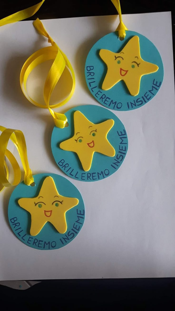 three tags with yellow stars on them are hanging from a ribbon next to a piece of paper