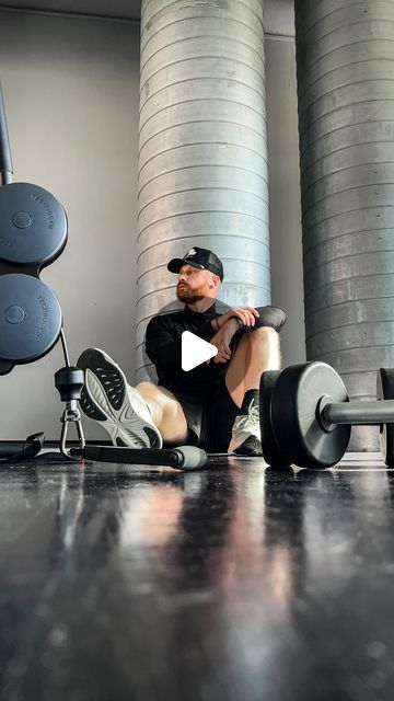 a man sitting on top of a bench next to a pair of dumbbells