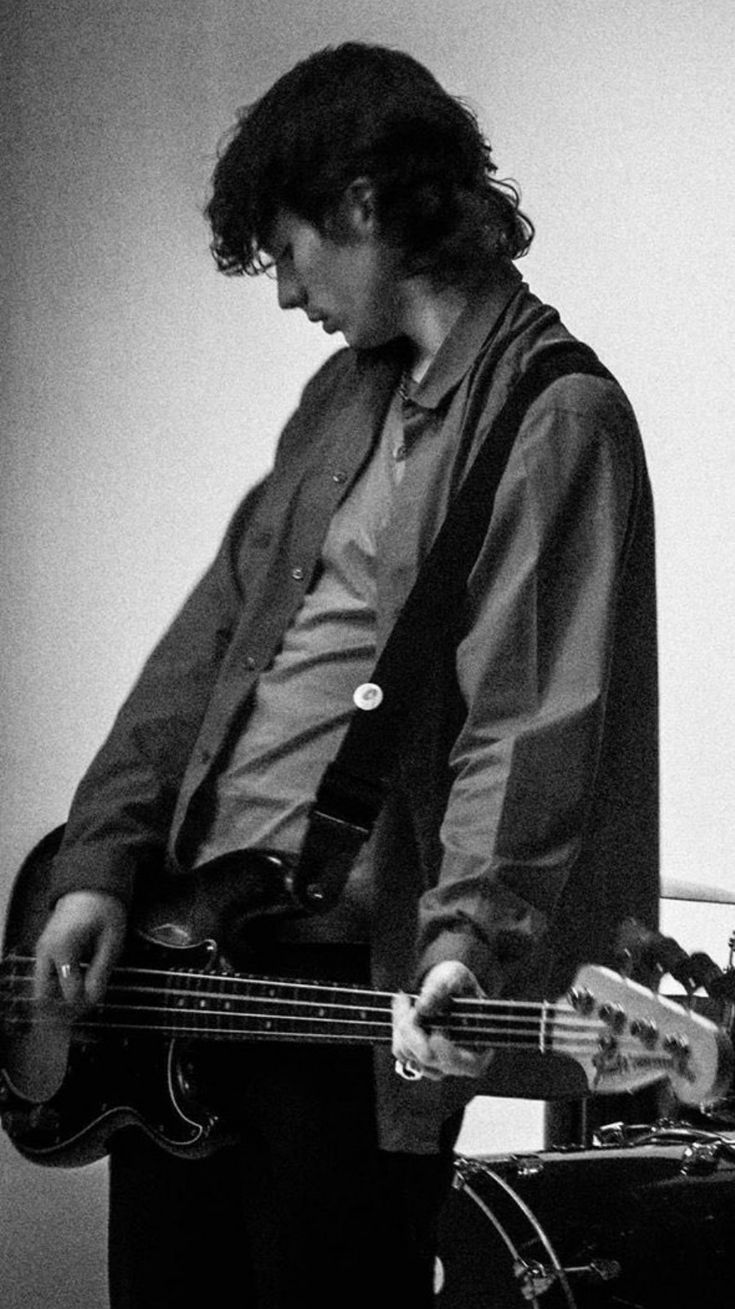 a young man is playing bass guitar in black and white