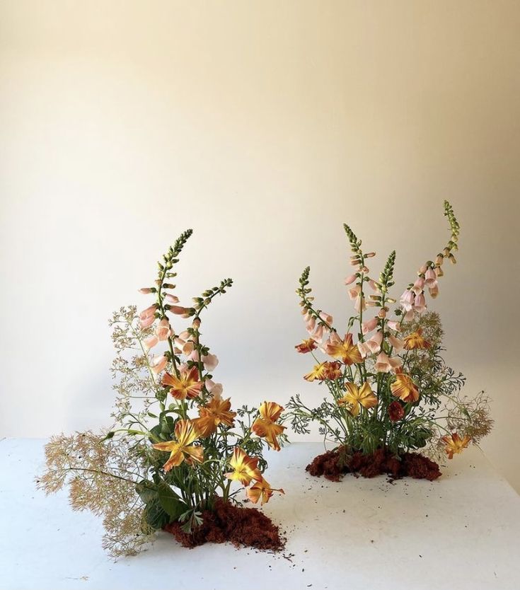 two vases filled with flowers sitting on top of a white table next to each other