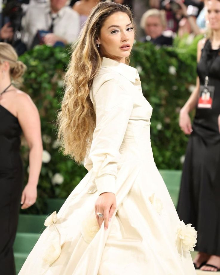 a woman in a white dress is walking down the red carpet with her hand on her hip