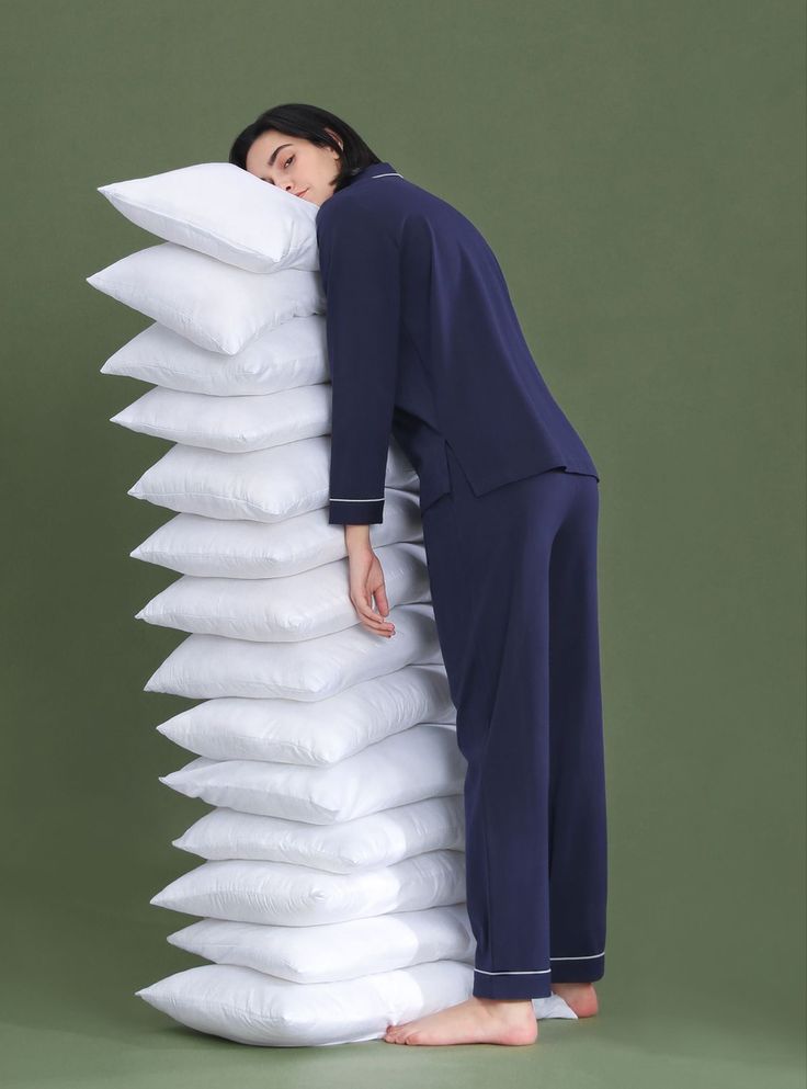 a woman leaning against a pile of pillows with her head on top of the pillow