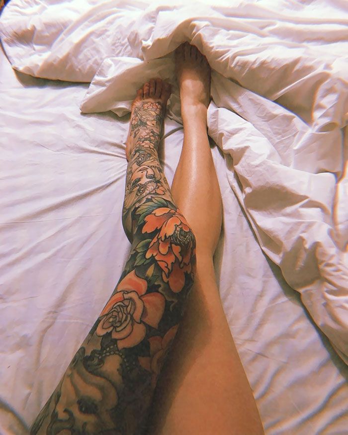 a tattooed person laying on top of a bed