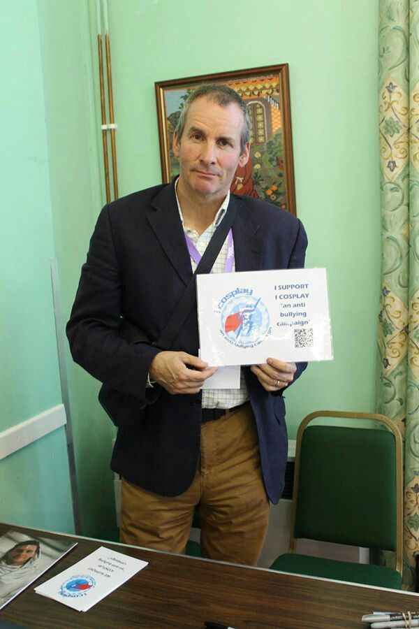 a man standing in front of a desk holding up a piece of paper with an award on it