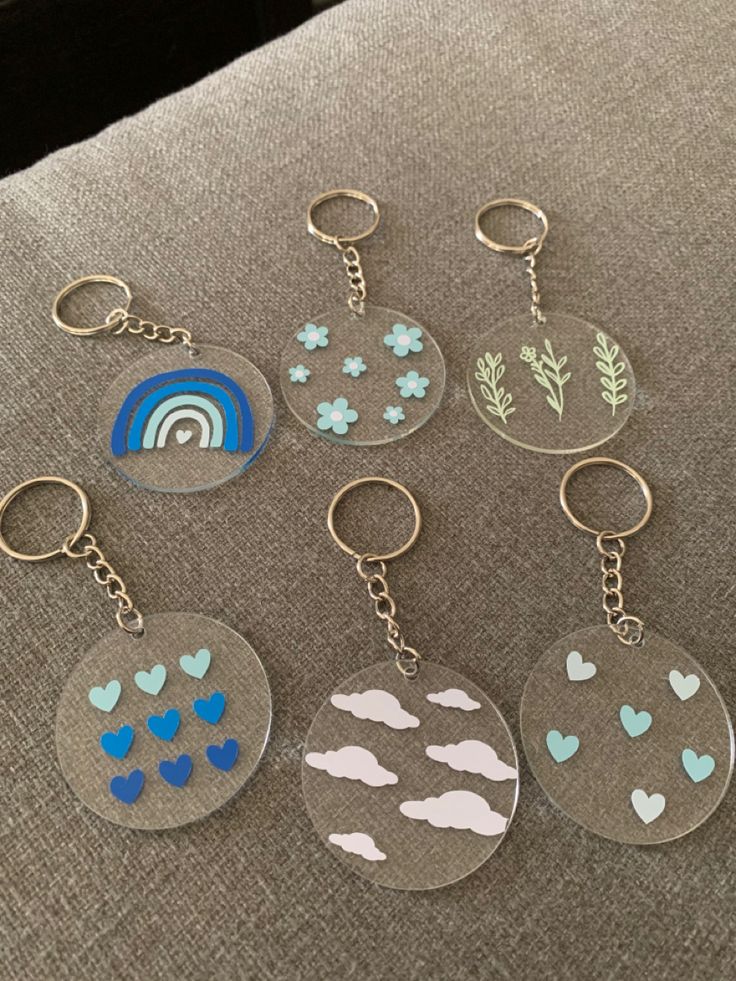 six keychains with different designs on them sitting on a couch in front of a window