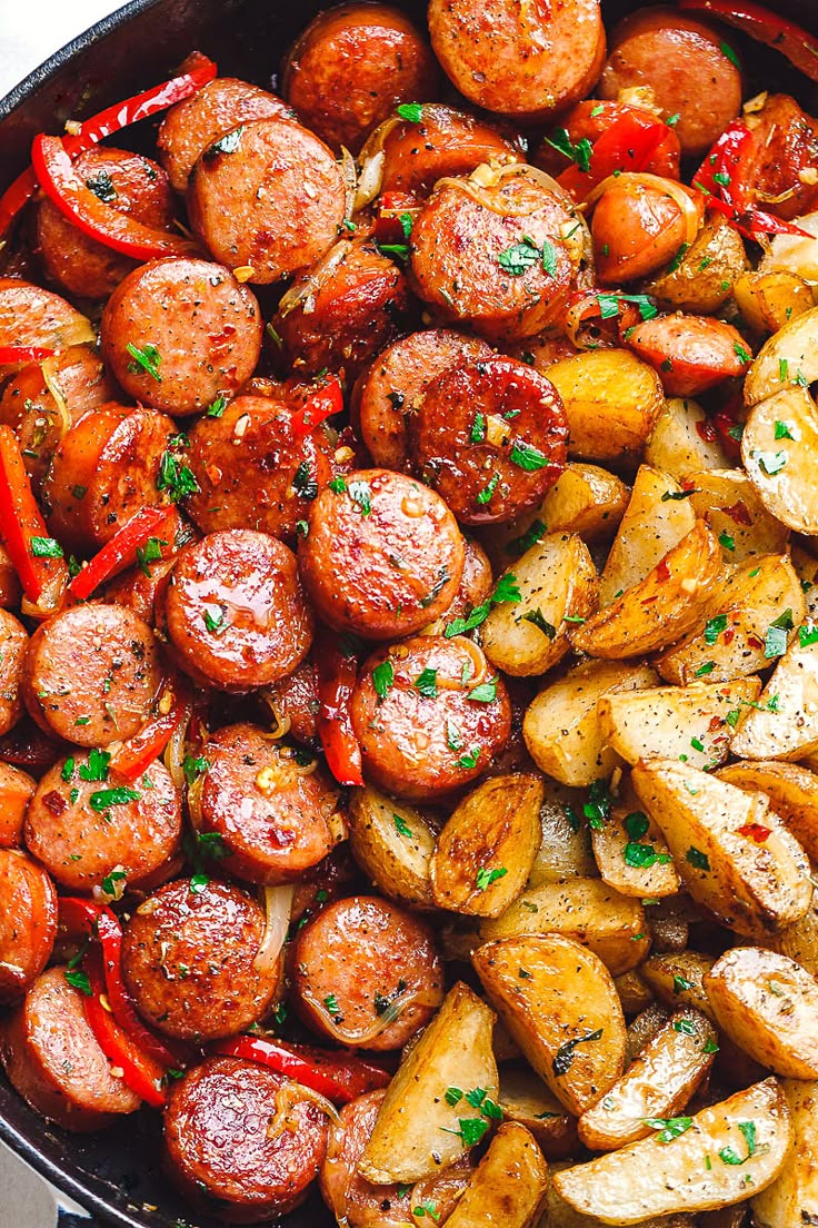 a skillet filled with potatoes and sausages, garnished with parsley