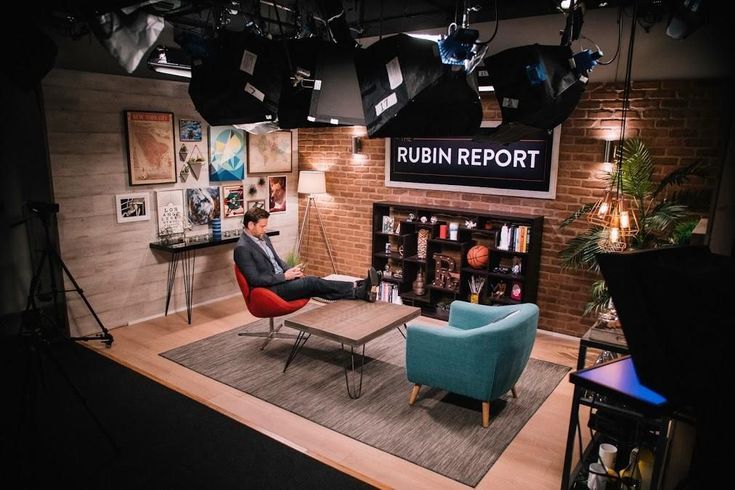 a man sitting in a chair on top of a rug next to a tv set