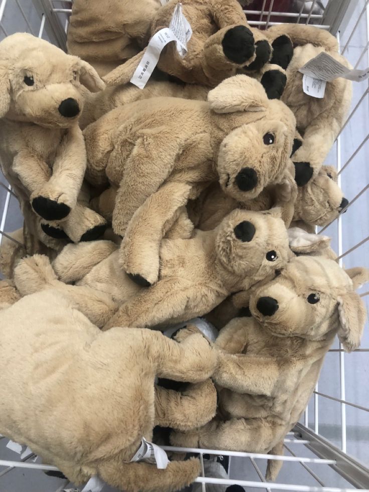 a pile of teddy bears sitting inside of a shopping cart with tags on it's ears