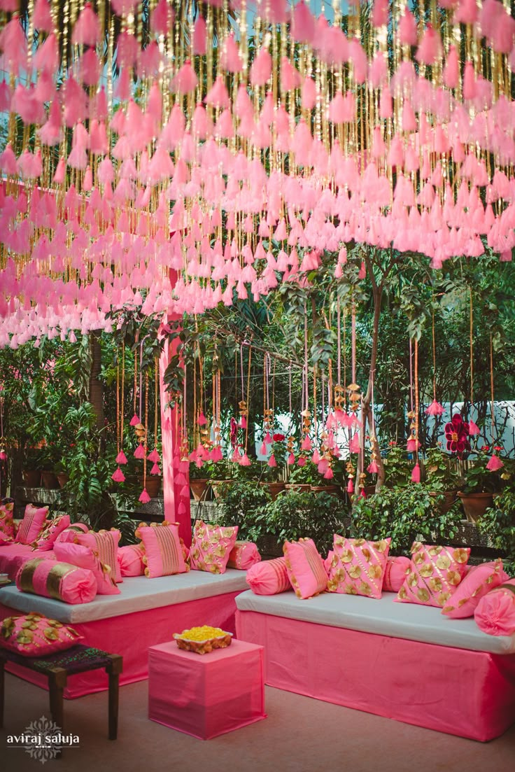 a room filled with lots of pink couches and flowers hanging from the ceiling above