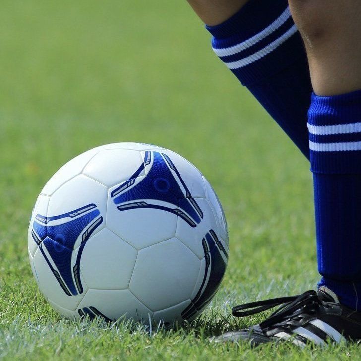 a soccer ball sitting on the ground next to a person's legs in blue and white socks