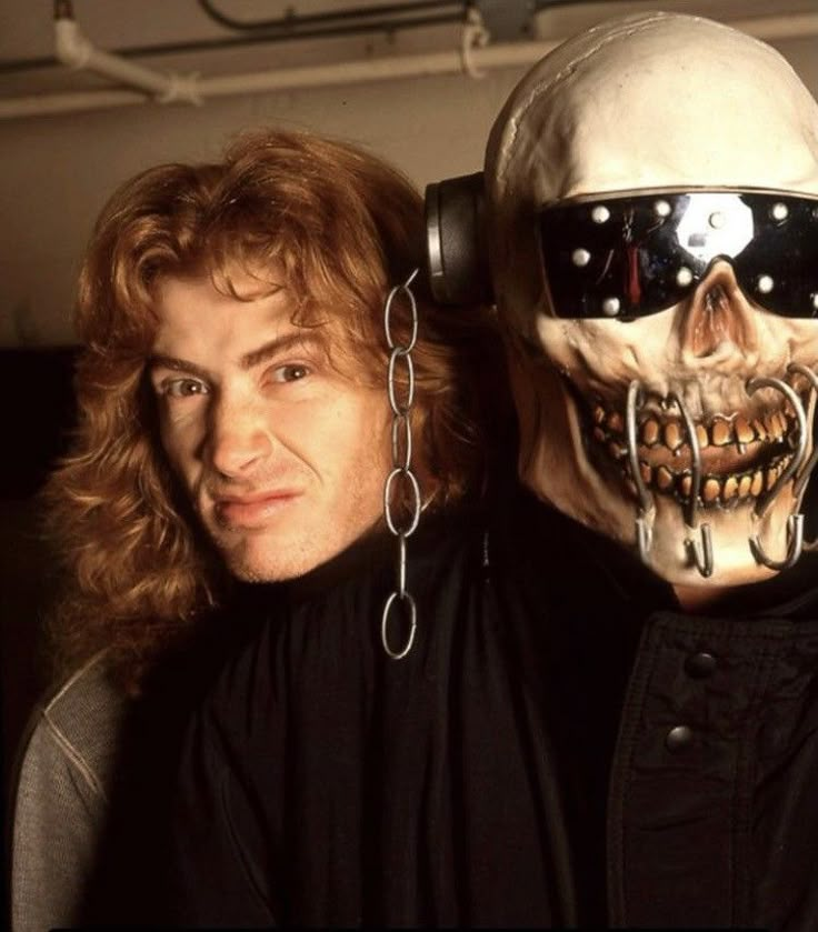 two men with chains around their necks and one wearing a skull mask