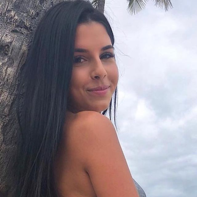 a beautiful woman standing next to a palm tree