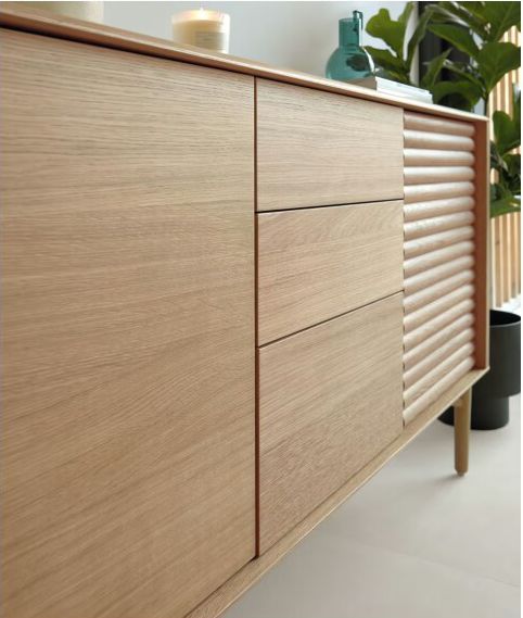 a large wooden cabinet sitting next to a plant on top of a white countertop