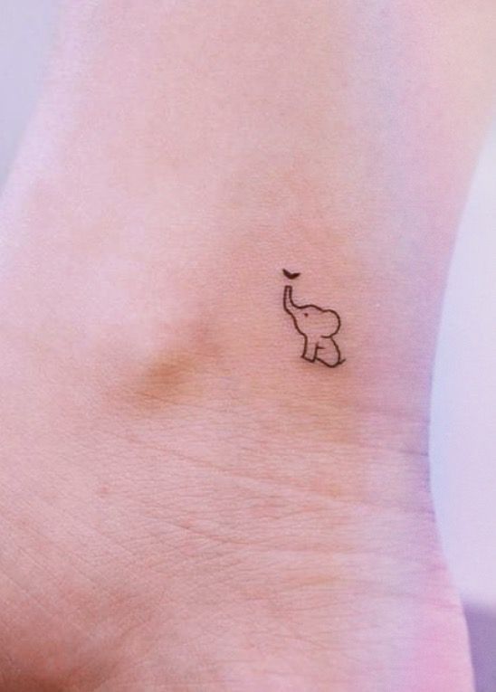 an elephant tattoo on the ankle that is black and white, with a small dot in the middle