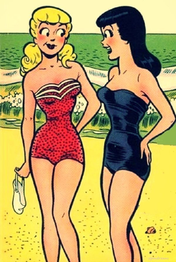 two women in swimsuits standing on the beach, one wearing a bathing suit