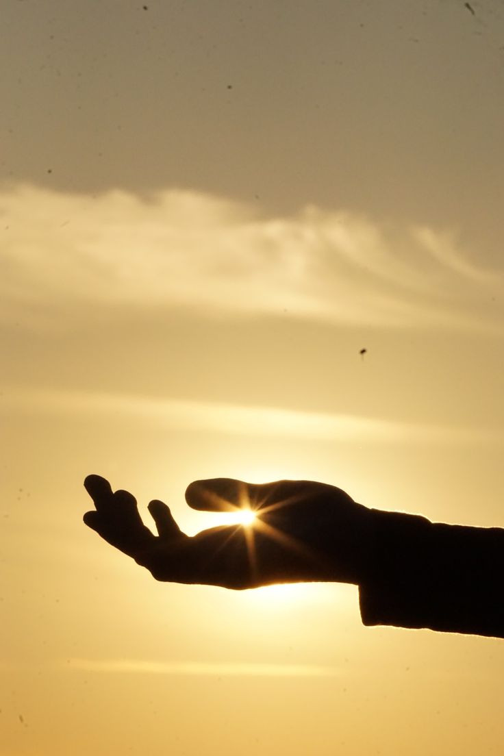 a person holding out their hand with the sun in the background