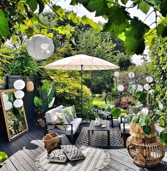 an outdoor patio with chairs, tables and umbrellas on the deck in front of trees