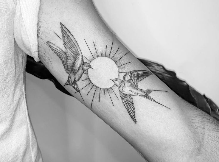 black and white photo of two birds flying in front of the sun tattoo on arm