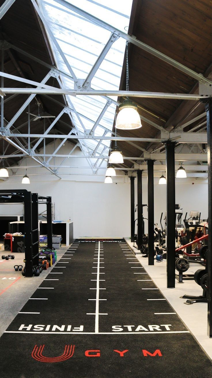 an indoor gym with black and white markings on the floor, overhead lighting and equipment