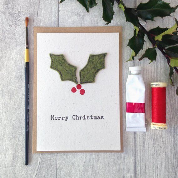 a christmas card with holly leaves on it next to a sprig of holly