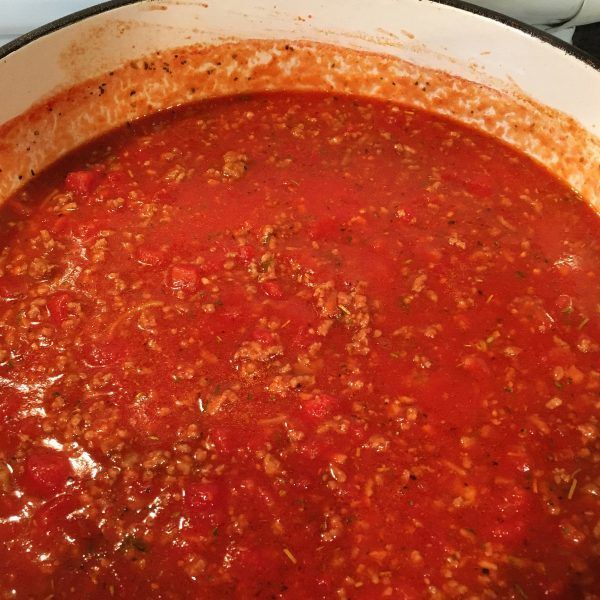 a pot filled with red sauce sitting on top of a stove