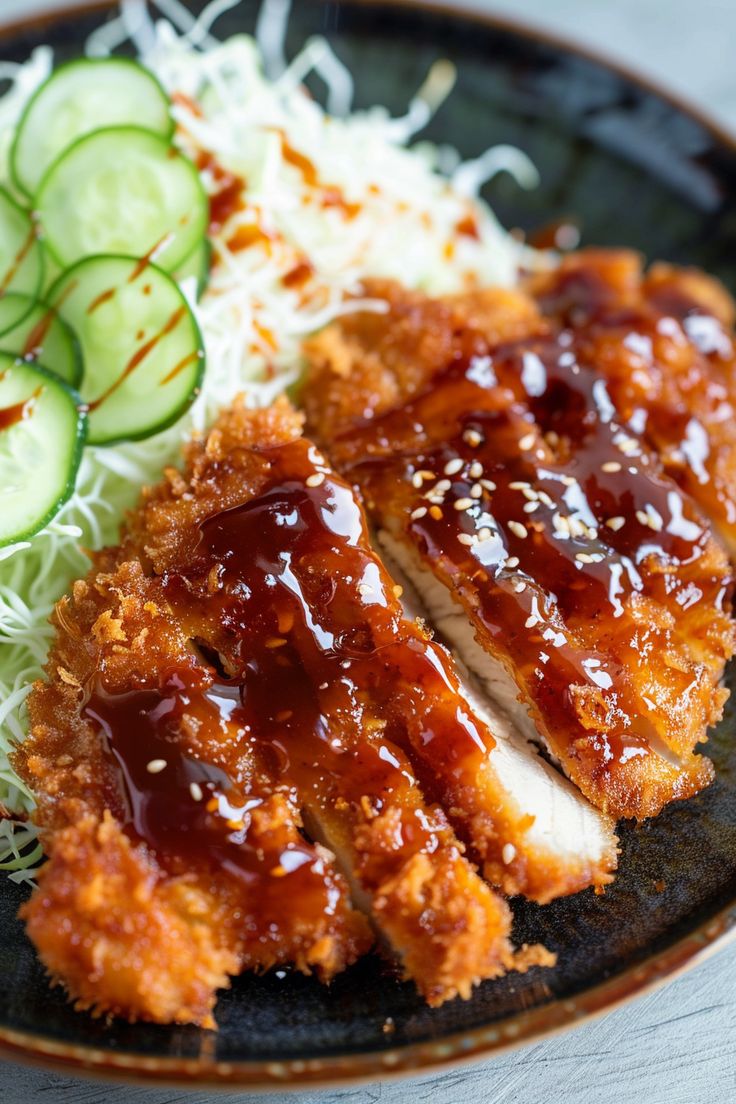 a black plate topped with meat covered in sauce next to cucumbers and grated cheese