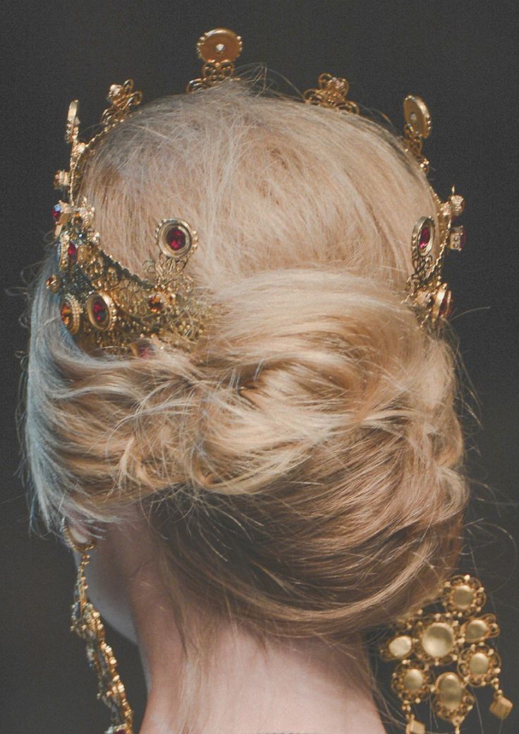 a woman with blonde hair wearing a gold tiara and earrings on her head, back view