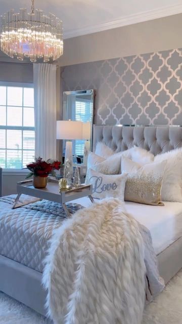 a bedroom with a large bed, chandelier and pillows on the headboard