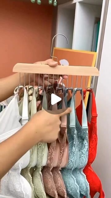 a woman is looking at bras hanging on a rack in a closet and pointing to them