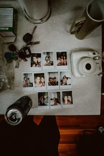 a table topped with lots of pictures and a camera next to a coffee cup on top of a counter