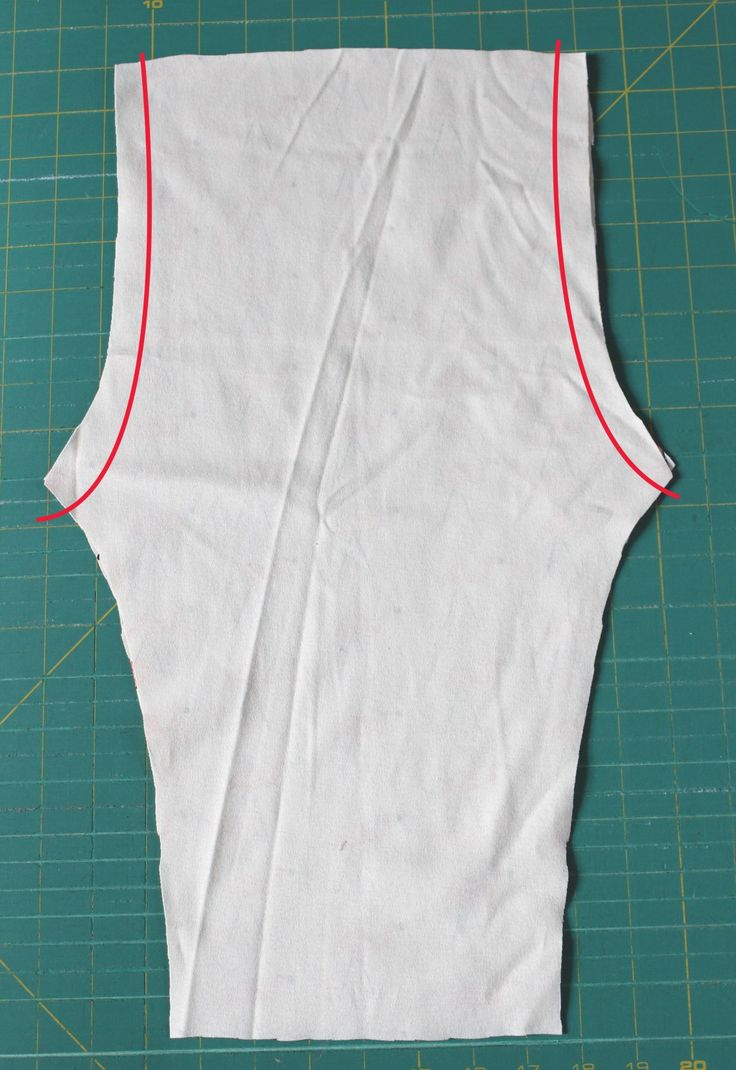 a piece of white fabric with red stitching on top of a green cutting mat