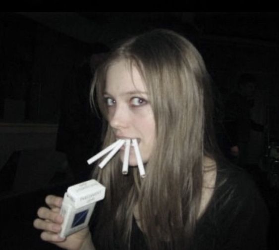 a woman with toothbrushes in her mouth is looking at the camera while holding something up to her mouth