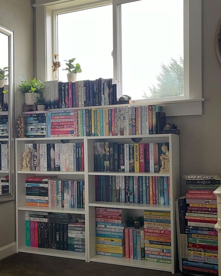 a bookshelf filled with lots of books next to a window