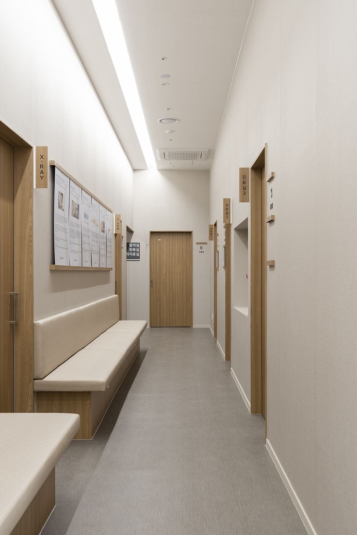 an empty hospital hallway with benches and posters on the wall above them, as well as wooden lockers